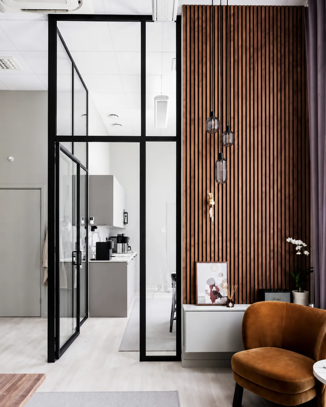 Floor-to-ceiling walnut slat wall beside glass office divider